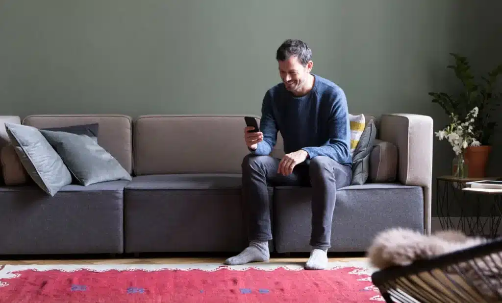 man on couch looking at phone